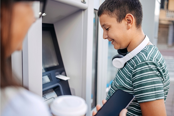 A teen using an ATM machine