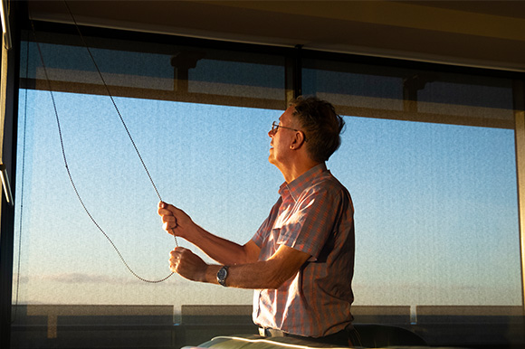 A man shutting blinds in his home